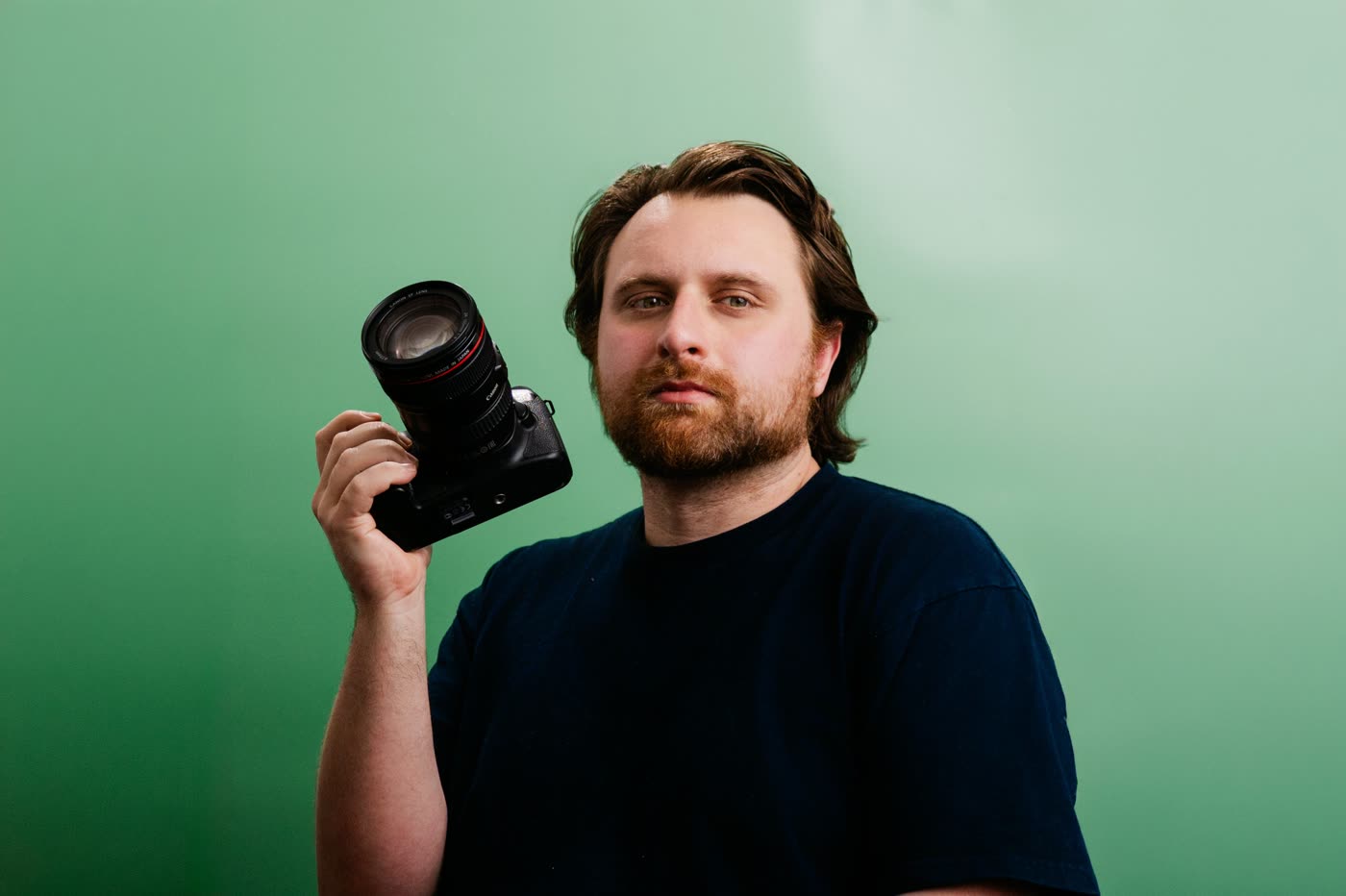 Jackson holding a camera in front of a green backdrop