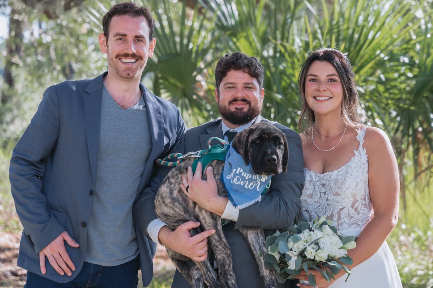 Two men and a woman posing with their dog