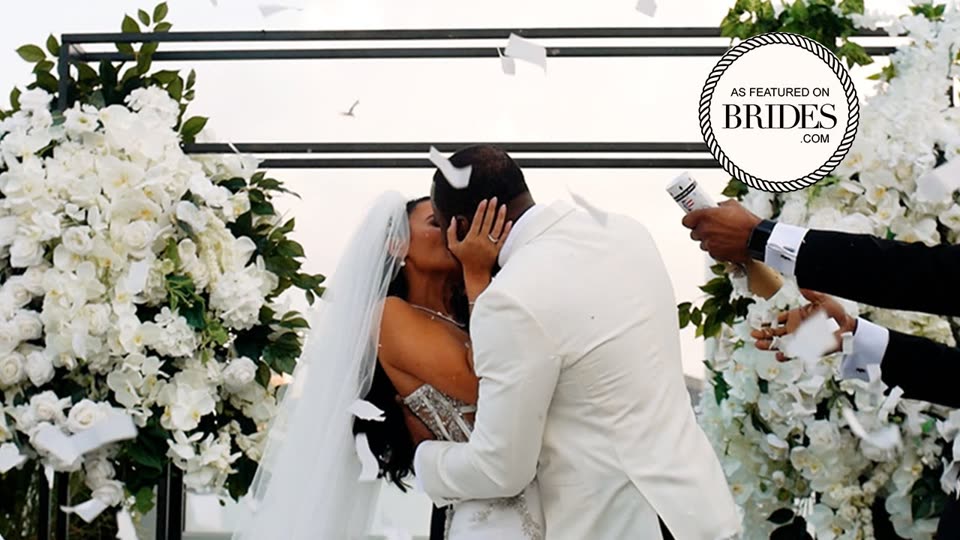 Couple kissing under a white floral arch on a Tribeca rooftop